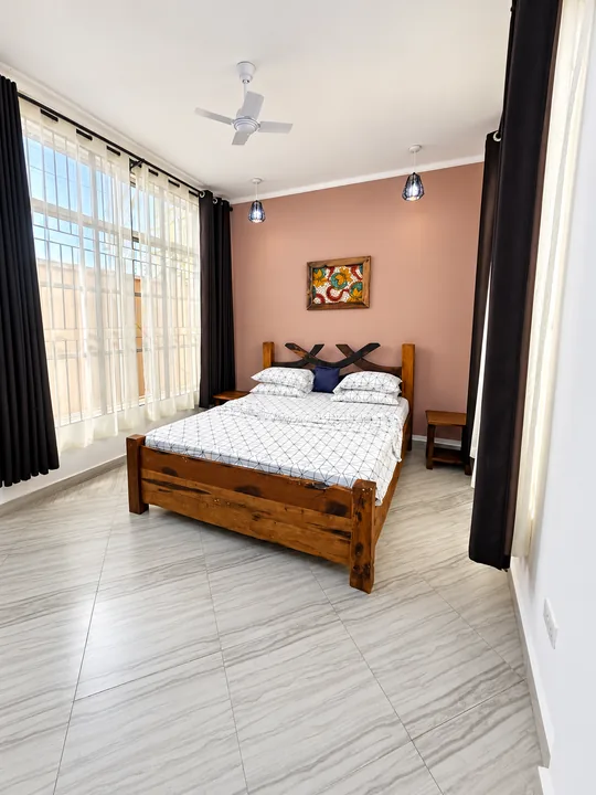 Double Room 703: wooden bed, pale blush accent wall and bright windows