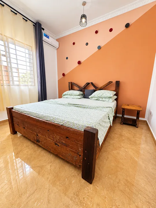 Double Room 704: wood-frame double bed with orange accent wall
